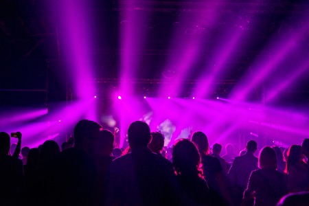 Concert Crowd. People silhouettes in front of bright stage lights. Band of rock starsの写真素材