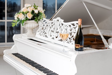 Grand piano in a luxury white classic interior with wine, palms and flowers.の写真素材