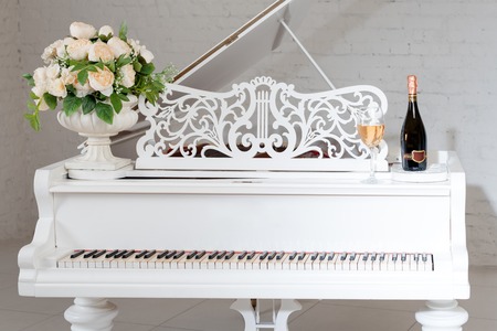 Grand piano in a luxury white classic interior with wine, palms and flowers.の写真素材