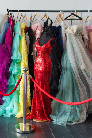 Many ladies evening gown long dresses on hanger in the dress rent shop for the wedding day or photo session. Dresses rental concept. Selective focus. Ball gown rental conceptの写真素材