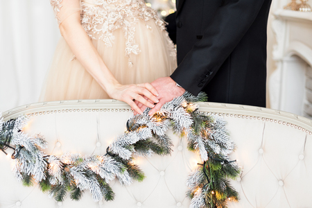 Pregnancy, winter holidays and people concept - close up of happy couple holding hands at Christmas.の写真素材
