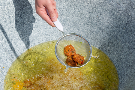 Male hands preparing falafel from chickpeas. Street food. Open kitchen international food festival event. Middle eastern fried chickepa balls, popular fast food mealの写真素材