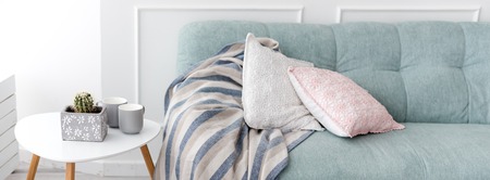 Modern wooden coffee table and cozy sofa with pillows. Living room interior and simple modern home decor concept.の写真素材