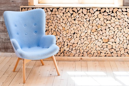 Comfortable soft armchair in scandinavian eco loft apartment. Modern minimalist living room with woodpileの写真素材