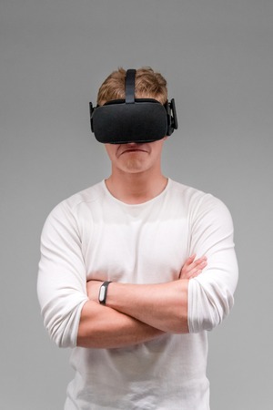 Man wearing virtual reality goggles on gray background. Student using VR headset.の写真素材