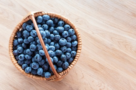 Blueberry in basket on wooden table background. Ripe and juicy fresh picked blueberries closeup, top view.の写真素材