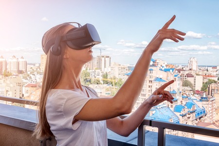 Young woman wearing virtual reality goggles headset, vr box outdoors. Connection, technology, new...