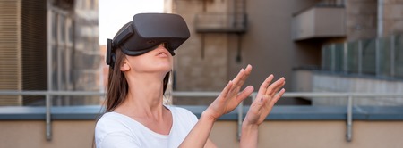 Young woman wearing virtual reality goggles headset, vr box outdoors. Connection, technology, new...