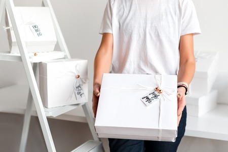 Unrecognizable woman holding Christmas gift in white boxes. Happy winter holidays. Presents for...