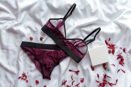 Set of glamorous stylish sexy lace lingerie with flowers on white bedsheets background. Woman accessories. Shopping and fashion concept.の写真素材