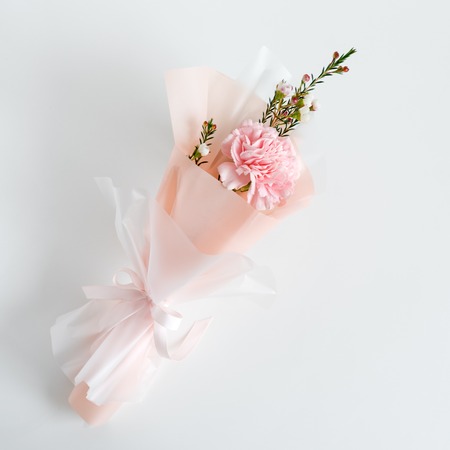 Spring flowers. Fresh bouquet with carnation in minimal style on light background. Top view, spring flat lay. Love and gift conceptの写真素材