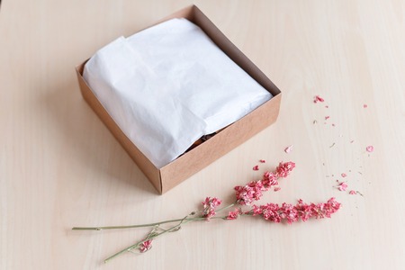 Brown craft paper gift box with dried flowers on wooden table. Selective focus.の写真素材