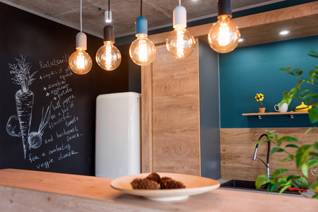Modern furniture in luxury kitchen. Minimalist scandinavian interior in loft apartment with wooden furniture, lamps, concrete elements and plantsの写真素材