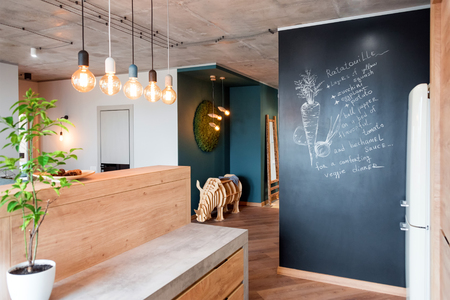 Modern furniture in luxury kitchen. Minimalist scandinavian interior in loft apartment with wooden furniture, lamps, concrete elements and plantsの写真素材