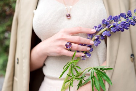 People, fashion, jewelry and luxury concept, closeup of woman wearing luxury jewelry standing on the street. Color gemstone ring and pendant with colored diamonds and gemstonesの写真素材