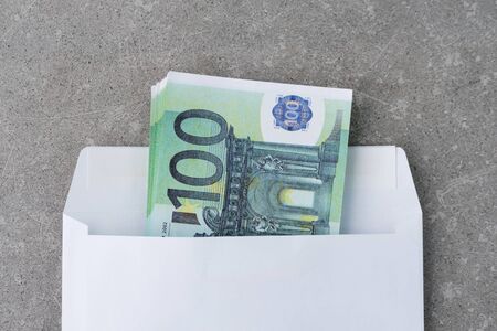 White envelope with a 100 euro bills.Stack of one hundred euro notes in open mail envelopeon concrete. A euro banknotes folded in an envelope as a present. Sending or saving money, corruption conceptの写真素材