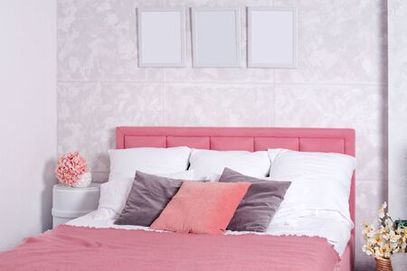 Stylish interior of modern bedroom. White and pink design of cozy bedroom with flowers. King-size bed with pink and grey bedding.の写真素材