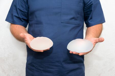 Doctor holding silicone implant for breast augmentation, space for text. Plastic surgeon hands...