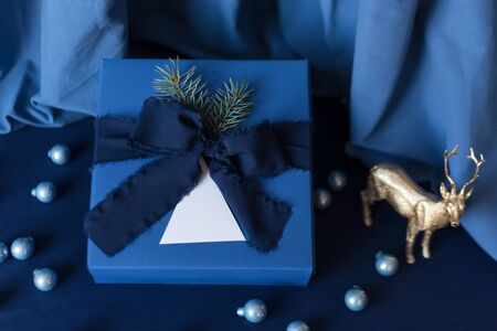New Year gifts, blue box on blue background with winter holidays decoration. Christmas background with gift box. Presents for Christmastime celebration.の写真素材