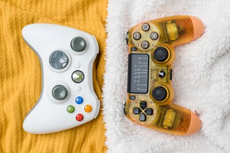 KIEV, UKRAINE - November 07, 2019: Xbox and Playstation 4 controllers together on colorful fabric backgroundのeditorial素材
