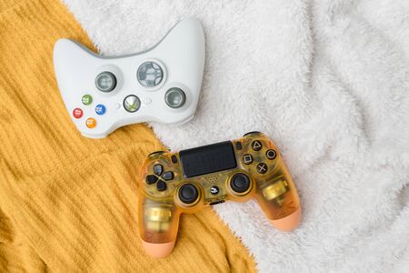 KIEV, UKRAINE - November 07, 2019: Xbox and Playstation 4 controllers together on colorful fabric...