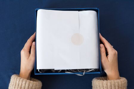 Unrecognizable woman holding gift in blue box. Happy winter holidays. Presents for Christmastime celebrationの写真素材