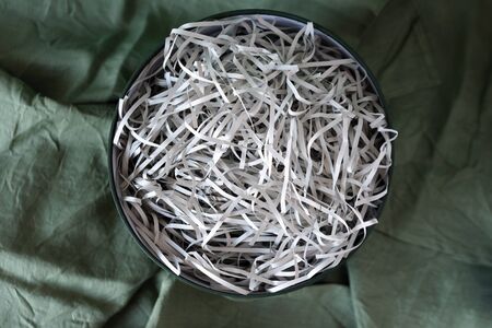 Opened gift box with decorative straw, filler, shavings, paper ribbons. Cut paper for packaging....