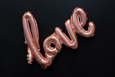 Love word from pink inflatable balloon on black background. The concept of romance, Valentine's Day....