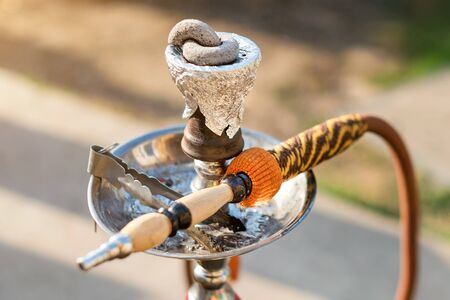 Hookah on blurred background. Cup for hookah stretched with foil and smoking coals