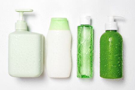 Different size and shapes containers for cleanser toner tonic conditioner, soap and shampoo on white background with water drops.Natural organic beauty products, blank label package, branding mock-upの写真素材