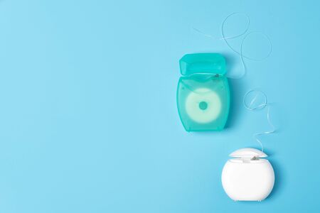 Dental floss containers on blue background. Daily oral hygiene, teeth care and health. Cleaning...