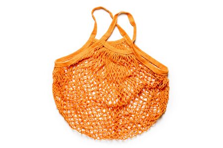 Empty reusable orange cotton shopping string bag on white background. Eco friendly net bag or shopper. Rejection of plastic, zero waste, recycle and reuse concept. Flat lay, space for text, top view.の写真素材