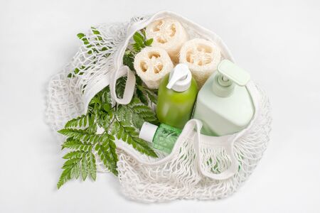 Different containers for lotion, shampoo, conditioner or liquid soap in eco bag. Loofah or luffa washcloth, vegetable sponge, alternative to plastic, zero waste, eco friendly. Natural beauty products.の写真素材