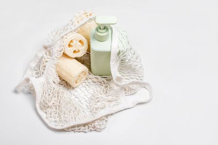 Green container for shampoo, conditioner or liquid soap in eco bag. Loofah or luffa washcloth, vegetable sponge, alternative to plastic, zero waste, eco friendly. Natural beauty products.の写真素材