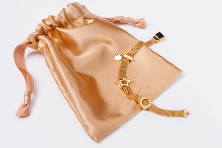 Gold bracelet on golden silk gift bag, jewelry flatlay on neutral background. Top view of fashion luxury woman accessories, jewelry and shopping concept. Trendy flat lay compositionの写真素材