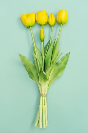 Yellow tulip flowers bouquet on mint background. Flat lay, top view. Minimal floral concept. Spring flowers, floral background with copyspace.の写真素材