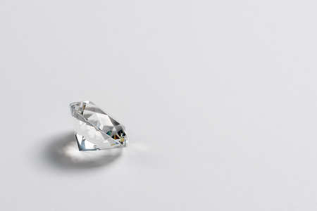 Dazzling diamond on neutral light background. Loose brilliant round diamond side view, copyspace.の写真素材