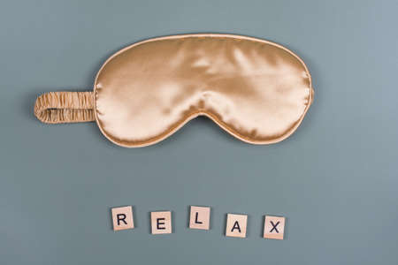 Word Relax and golden sleeping eye mask, top view. Good night, flight and travel concept. Sweet...