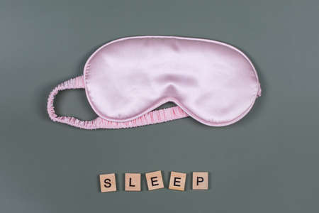 Word SLEEP and pink sleeping eye mask, top view. Good night, flight and travel concept. Sweet dreams, relax, siesta, insomnia, relaxation, tired, travel concept. Do not disturb, bedtime conceptの写真素材