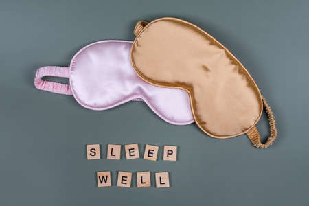 Words SLEEP WELL and sleeping eye masks, top view. Good night, flight and travel concept. Sweet dreams, relax, siesta, insomnia, relaxation, tired, travel concept. Do not disturb, bedtime conceptの写真素材