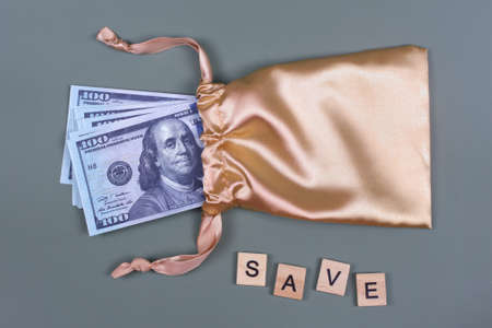 Money in golden gift bag with word SAVE. Saving investing concept. American currency, cash, bonus, monetary prize, pile of 100 dollar billsの写真素材