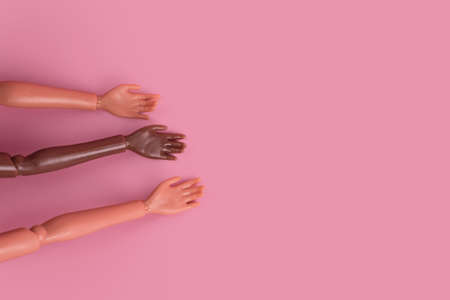 Three doll hands on pink background. Different skin tones and races. Stop racism, diversity and unity, equality and feminism creative concept. Place for text, top view, layout.の写真素材
