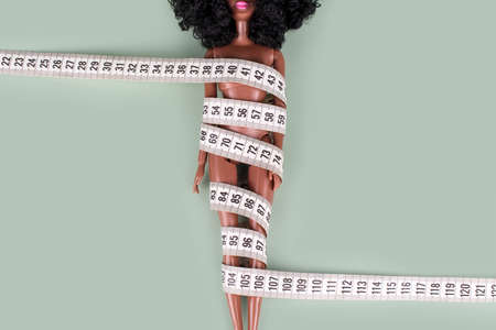 Doll wrapped in measuring tape. Tied up unrecognizable plastic doll, weight loss, fasting and...