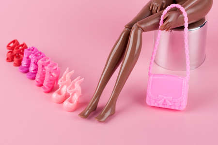 Long skinny legs of a plastic toy doll and stylish shoes on pink background. Plastic doll trying on high heels shoes.Woman choosing new shoes, deciding which pair to buy. Fashion and shopping conceptの写真素材