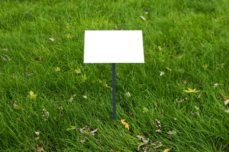 Empty sign board on grass with space for caption. Property house for sale sign board. Notice board with copyspace for prohibition.の写真素材