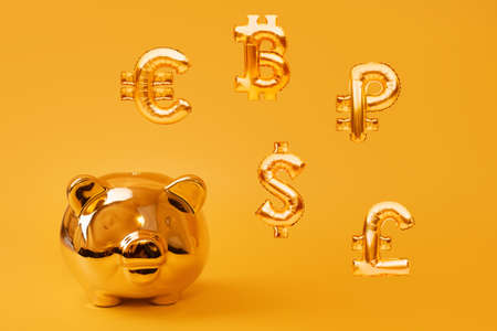 Golden piggy bank on yellow background with golden currency symbols made of inflatable foil...