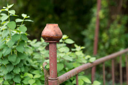 Clay jug hanging on the fence in the garden. Traditional ukrainian pottery. Brown pottery used as garden decor.の写真素材