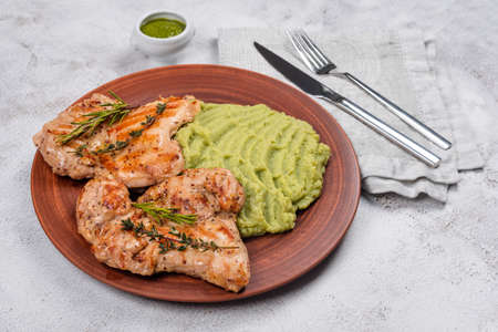 Delicious grilled chicken with herbs and green puree. Chicken fillet with mashed potatoes, green peas and pesto sauce. Healthy homemade foodの写真素材