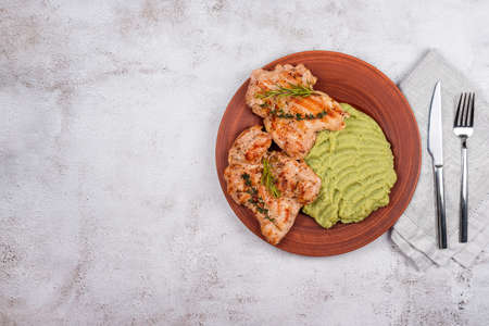 Delicious grilled chicken with herbs and green puree. Chicken fillet with mashed potatoes, green peas and pesto sauce. Healthy homemade food. Flat lay, top view, space for text.の写真素材