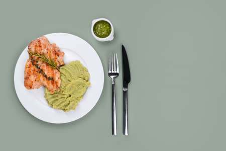 Delicious grilled chicken with herbs and green puree. Chicken fillet with mashed potatoes, green peas and pesto sauce. Healthy homemade food. Flat lay, top view, space for text.の写真素材